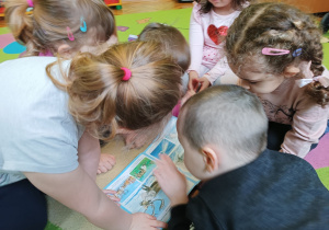 Dzieci oglądają książkę z obrazkami niedźwiedzia polarnego.