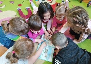 Dzieci oglądają książkę z obrazkami niedźwiedzia polarnego.