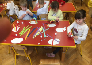 Dzieci przyklejają paski papieru kolorowego.
