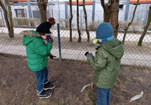 Chłopcy szukają oznak wiosny przy użyciu lornetek.