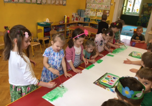 Dziewczynki malują farbami na kartonie.