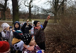 Dzieci stoją i szukają oznak wiosny z użyciem lornetek.