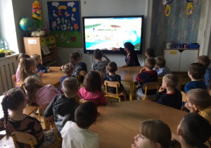 Dzieci siedzą przed monitorem i oglądaja film edukacyjny.
