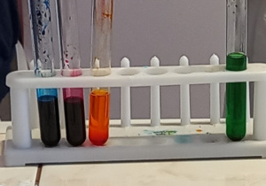 Dzieci stoją przy stole i wykonują eksperyment z kolorami.