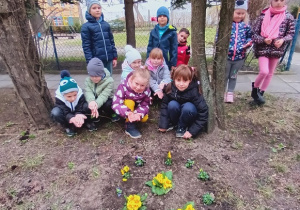 Grupowe zdjęcie dzieci przy posadzonych kwiatach.