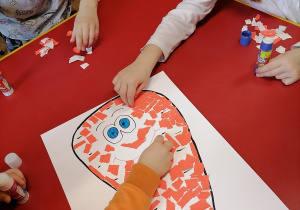 Dzieci wyklejają marchewkę papierem kolorowym.