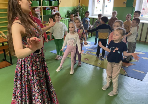 Dzieci naśladują ruchy za instruktorką w ukraińskim stroju ludowym.