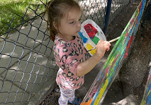 Dziewczynka stoi i maluje pędzlem na folii.