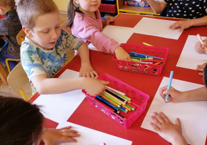 Dzieci rysują na kartonach.