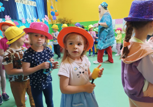 Zdjęcie dzieci w kapeluszach, grających na instrumentach muzycznych.