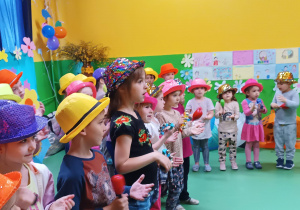 Zdjęcie dzieci w kapeluszach, grających na instrumentach muzycznych.