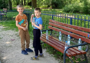 Zdjęcie chłopców stojących przy ławce.