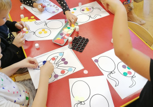 Dzieci naklejają kolorowe koła.
