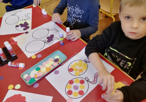 Dzieci wyklejają kolorowymi kołami.