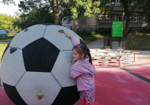 Dziewczynka wspina sie na piłkę.