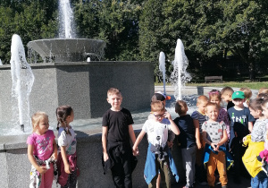 Dzieci stoją przy fontannie.