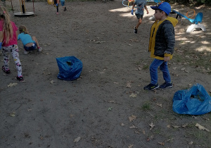 Dzieci zbierają śmieci z ogrodu.