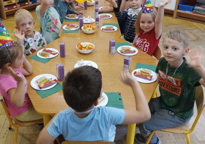 Zdjęcie dzieci siedzących przy stole podczas poczęstunku.