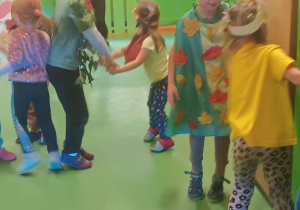 Dzieci przebrane w stroje drzew tańczą do muzyki.