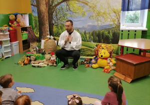 Dzieci słuchają opowiadania mężczyzny.
