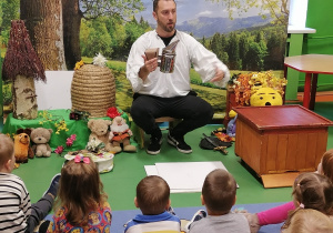 Mężczyzna pokazuje dzieciom podkurzacz pszczelarski.