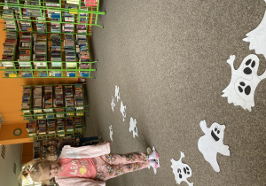 Dziewczynka stoi na papierowej sylwecie ducha.