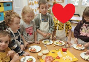 Zdjęcie dzieci przy stole z przygotowanymi kanapkami.