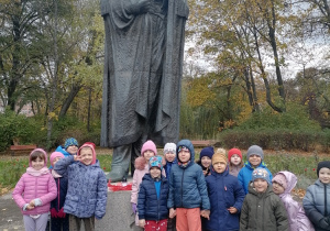 Dzieci stoją przed pomnikiem St. Staszica.