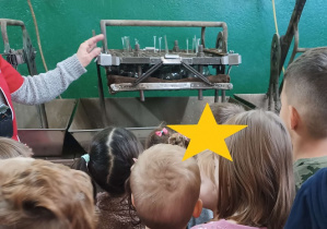 Zdjęcie dzieci stojących przy maszynie srebrzejącej bombki.