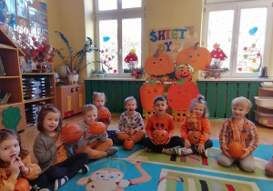 Dziecko siedzi na dywanie i opowiada o dyni.