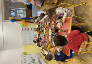 Dzieci siedzą przy urodzinowym stole.