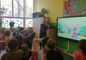 Dzieci stoją przed tablicą interaktywną