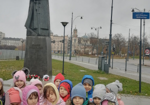 Dzieci stoją przed pomnikiem.