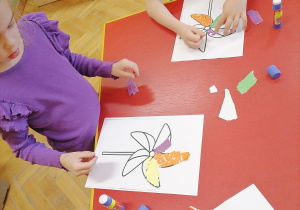 Dziecko nakleja kolorowe kawałki papieru.