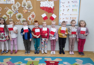 Dzieci trzymają w rączkach zrobione samodzielnie flagi Polski.