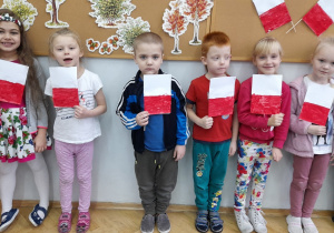 Dzieci trzymają w rączkach zrobione samodzielnie flagi Polski.