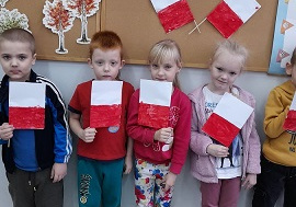 Dzieci trzymają w rączkach zrobione samodzielnie flagi Polski.