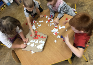 Dzieci wypełniają kontur mapy Polski serduszkami.