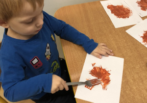 Chłopiec maluje widelcem.