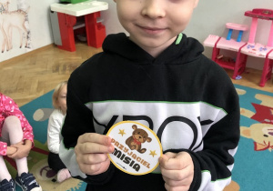 Chłopiec prezentuje odznakę przyjaciela pluszowego misia.