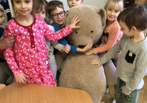 Dzieci tulą ogromnego pluszowego misia.