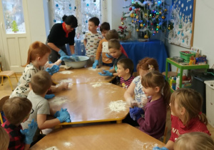 Dzieci z nauczycielem przygotowują ciasto na pierniczki.