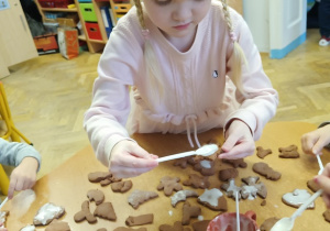 Dziewczynka lukruje pierniczki.