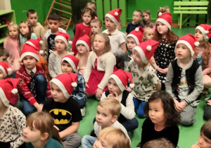 Dzieci siedzą i słuchają Świętego Mikołaja.