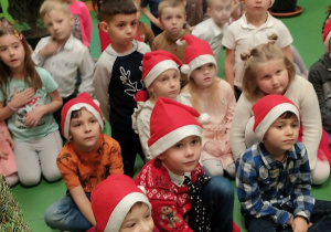 Dzieci siedzą i słuchają Świętego Mikołaja.