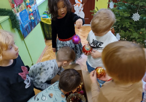 Dzieci wyciągają bombki z pudełka.