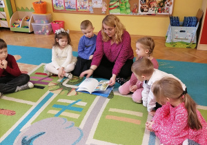 Kobieta czyta książkę z domowej biblioteczki.