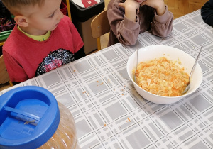 Dzieci siedzą przy stoliku i będą jeść surówkę.