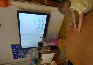 Dzieci rysują na ekranie interaktywnym dotykowym.