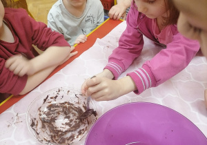 Dzieci mieszają czekoladę w misce.